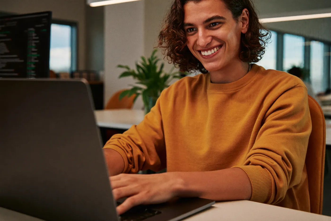 A developer smiling while working at a laptop