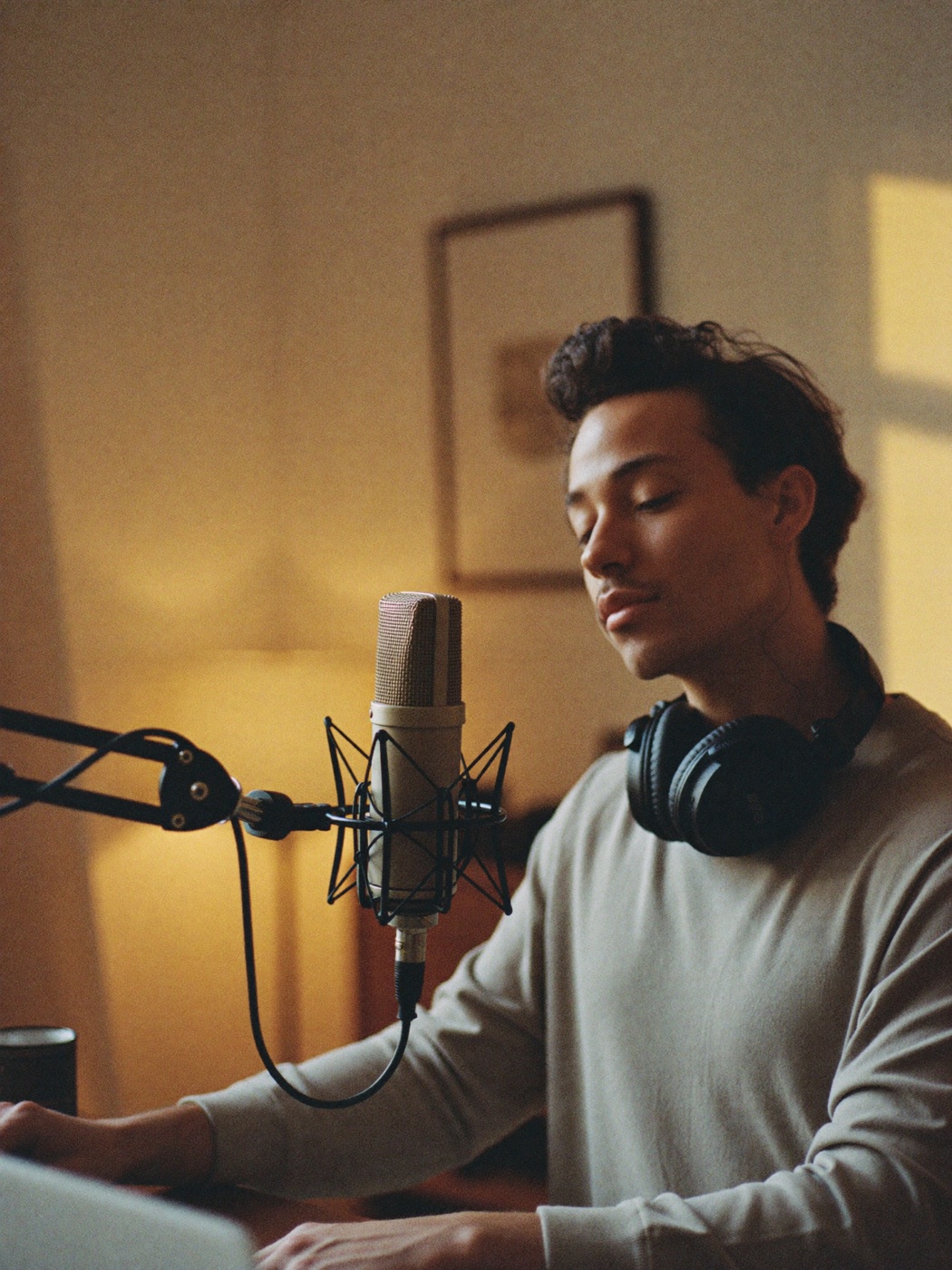 A content creator recording in a warm home studio, microphone in the foreground