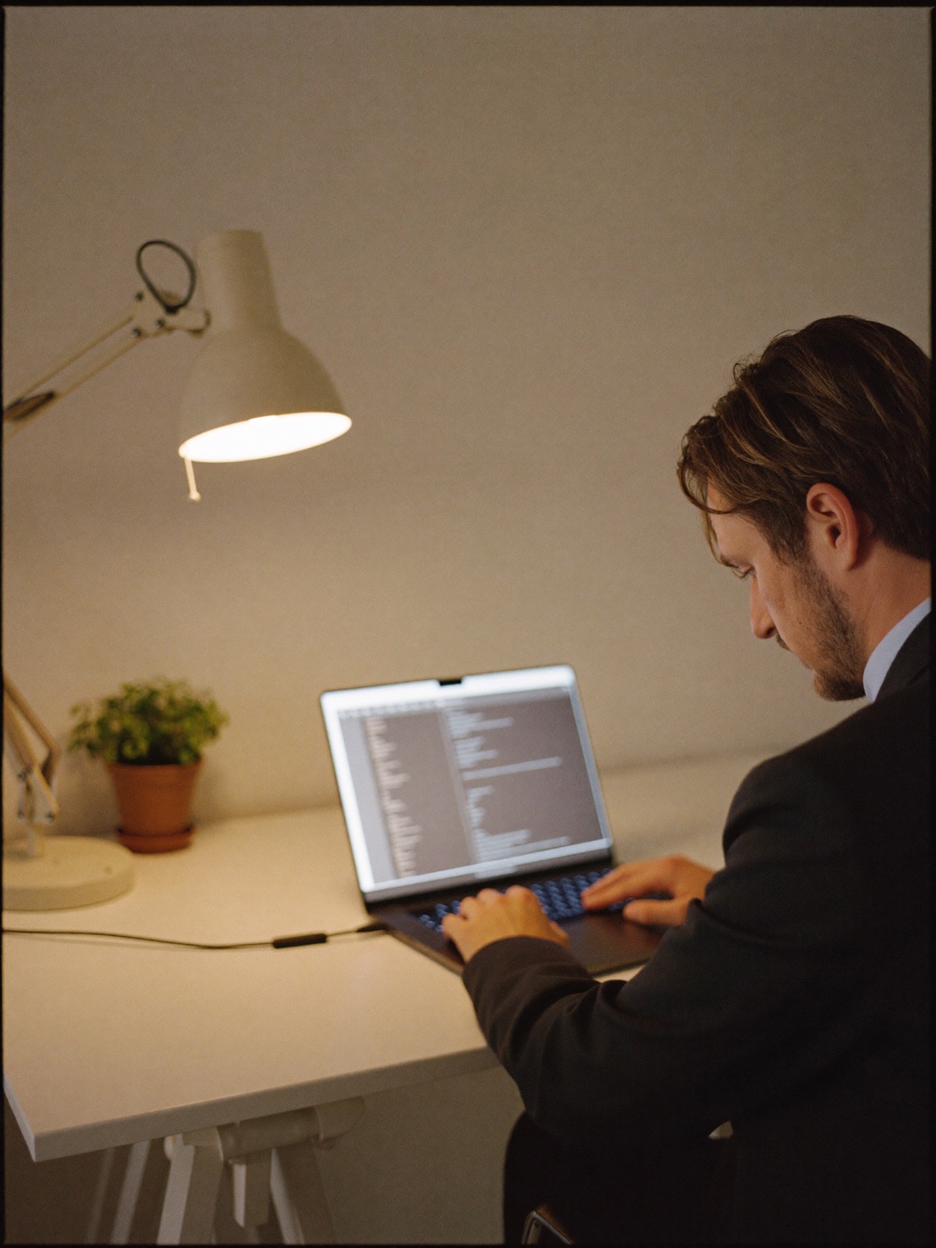 A focused developer at a minimal desk with a laptop showing soft code