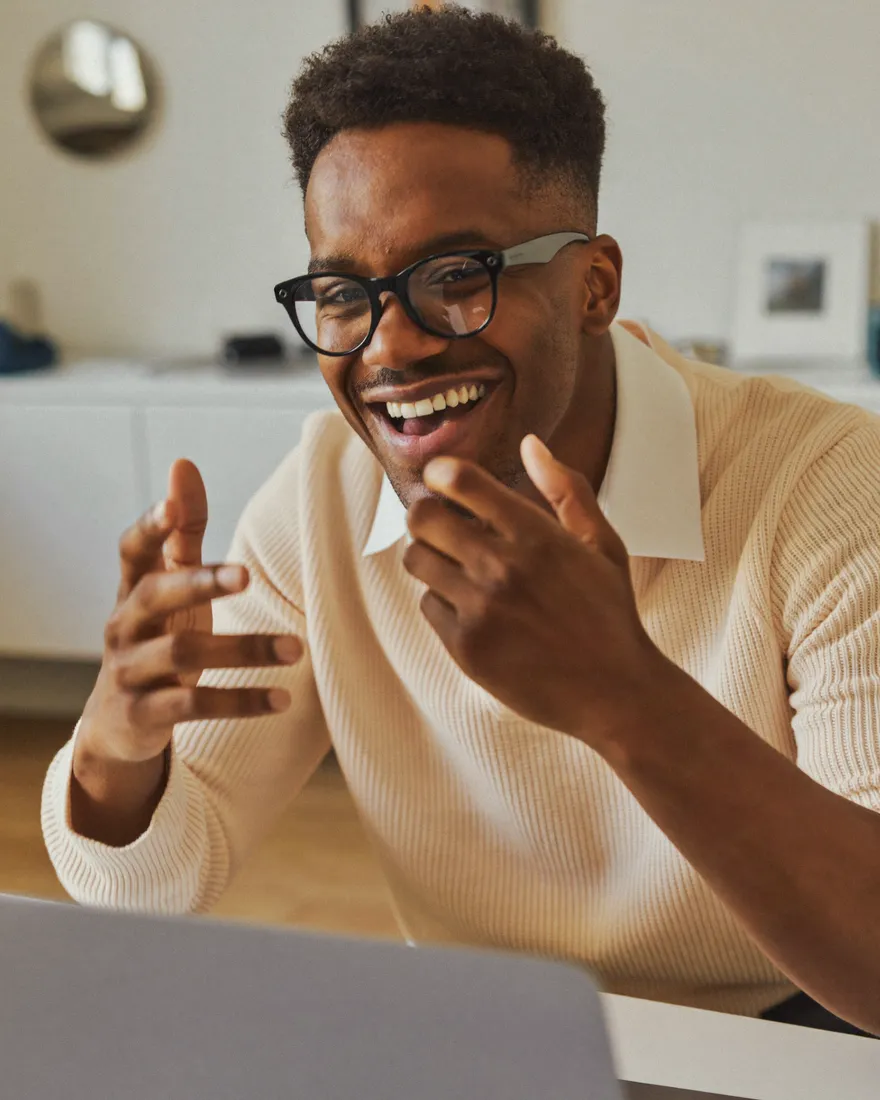 A person smiling and gesturing during a live video call on a laptop